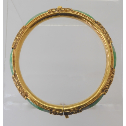 2794 - AN ORIENTAL BANGLEmade in bright yellow metal chased with different plants and flowers and set with ... 