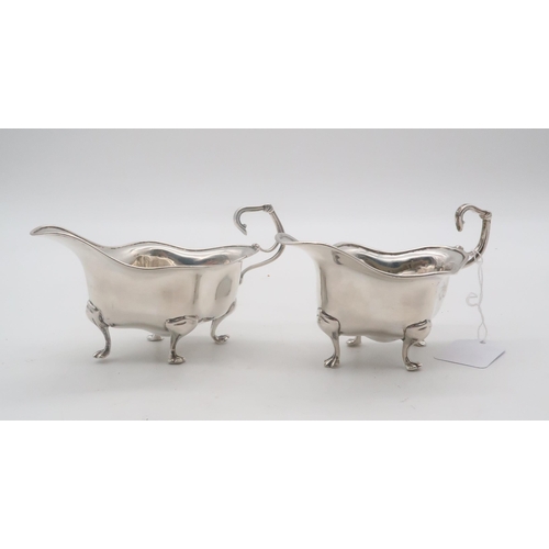 449 - A pair of silver sauce boats, by Walker & Hall, Sheffield 1907, of shaped form, on four pad feet... 