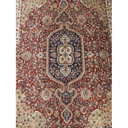 56 - A red floral patterned ground Kashmiri rug with dark blue central medallion, beige spandrels and dar... 