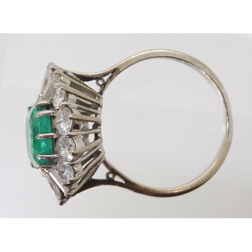 2750 - AN EMERALD & DIAMOND CLUSTER RINGset with a step cut emerald of approx 8.95mm x 8.33mm x 4.6mm i... 