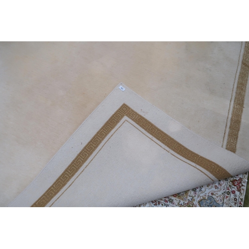 139 - A contemporary cream ground rug with key design border, 275cm long x 209cm wide