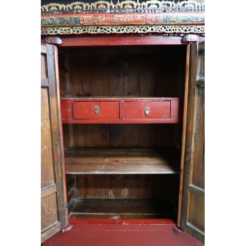 14 - A 20th century red painted Oriental cabinet with carved pierced surmount over pair of cabinets with ... 