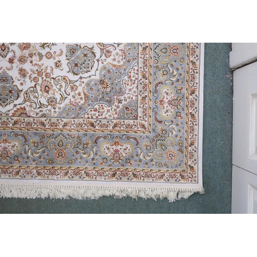 32A - A cream floral patterned ground Tabriz rug with light blue central medallion, matching spandrels and... 