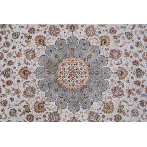 32A - A cream floral patterned ground Tabriz rug with light blue central medallion, matching spandrels and... 