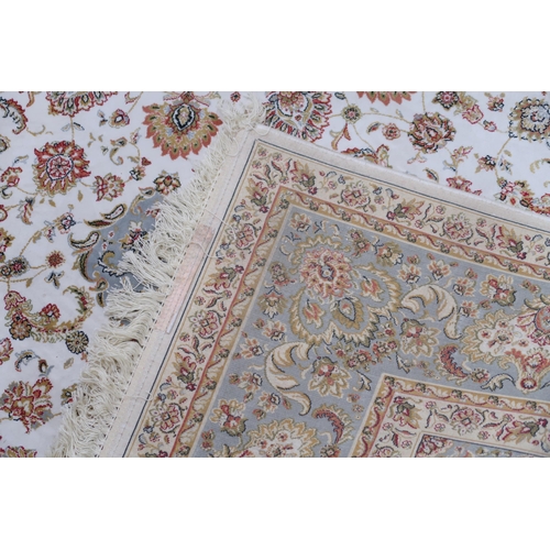 32A - A cream floral patterned ground Tabriz rug with light blue central medallion, matching spandrels and... 