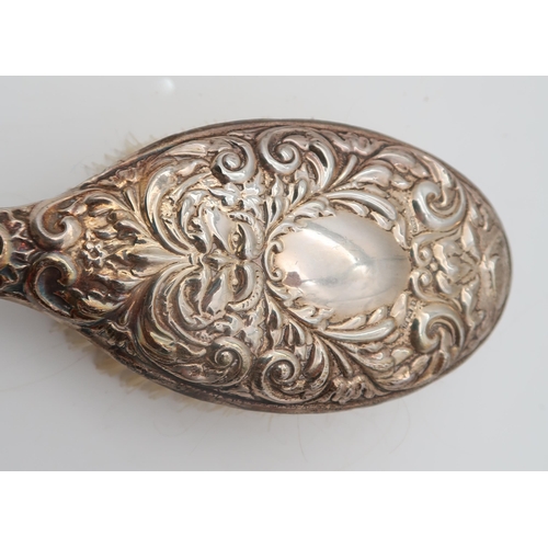 384 - A three piece silver dressing set, Birmingham marks, cast with scrolling foliate mask decoration, an... 