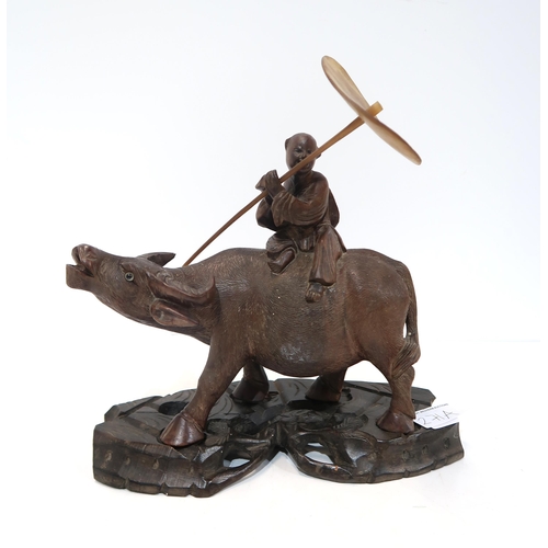 271A - A Chinese carved figure of a boy carrying a horn parasol&nbsp; riding a water buffalo, on a naturali... 