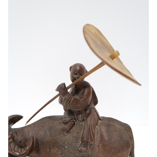 271A - A Chinese carved figure of a boy carrying a horn parasol&nbsp; riding a water buffalo, on a naturali... 