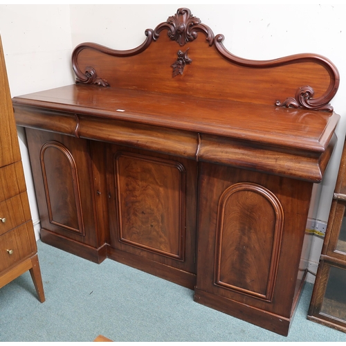 102 - A Victorian mahogany sideboard with carved shaped splashback over three drawers over three inverted ... 