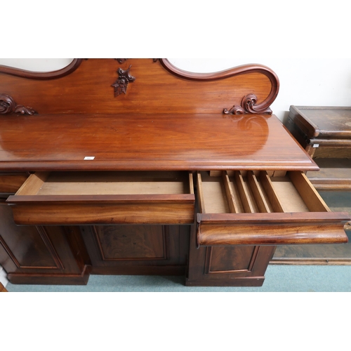 102 - A Victorian mahogany sideboard with carved shaped splashback over three drawers over three inverted ... 