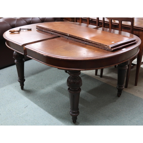 119 - A Victorian mahogany oval wind out extending dining table with two spare leaves on turned supports, ... 