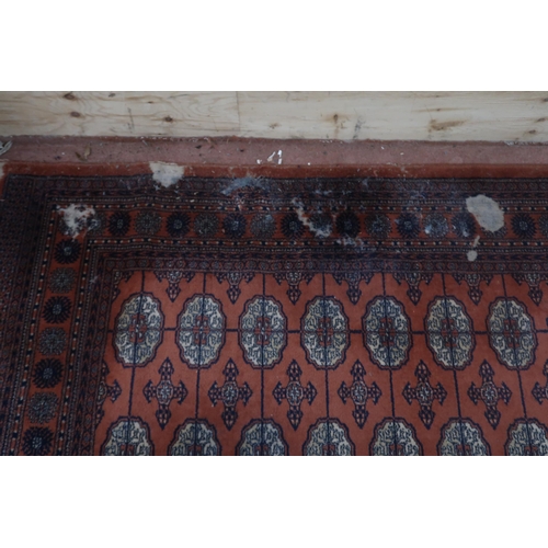 124 - A pair of terracotta ground Bokhara rugs with all over lozenge design and multicoloured border, 364c... 