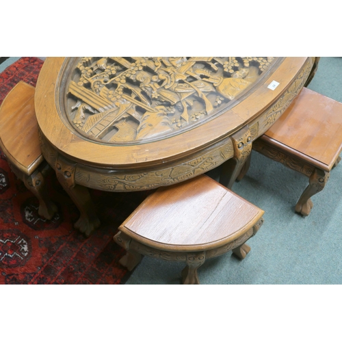 24 - An early 20th century Chinese hardwood oval nesting coffee table with carved top depicting village s... 