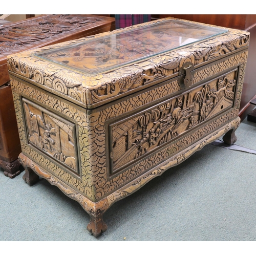 25 - A 20th century Chinese camphorwood blanket chest carved with village scenes on shaped feet joined by... 