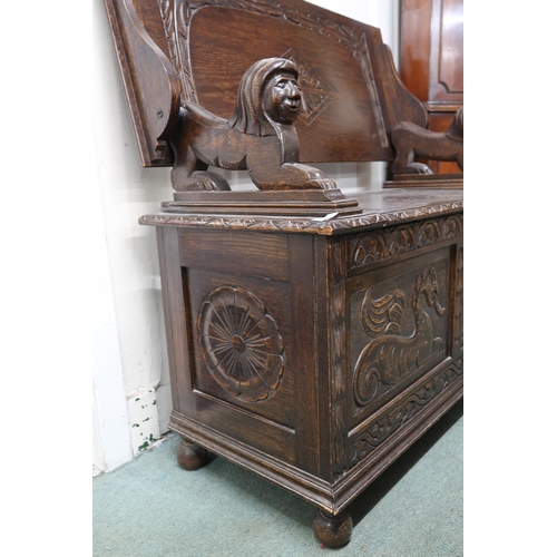 32 - A 20th century oak monks hall bench with hinged top on lion form arms over hinged chest base carved ... 