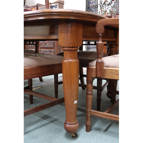 43 - A Victorian wind out extending dining table and eight sabre legged dining chairs, table with two spa... 