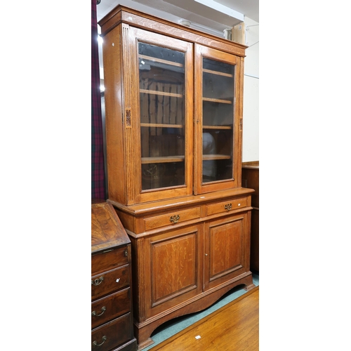 64 - A late Victorian oak bookcase with moulded cornice over pair of glazed doors on base with two drawer... 