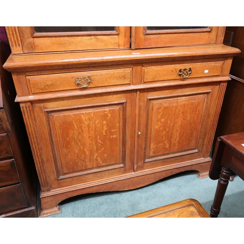 64 - A late Victorian oak bookcase with moulded cornice over pair of glazed doors on base with two drawer... 