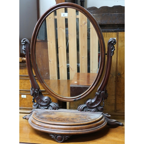 81 - A Victorian walnut dressing mirror with oval pane suspended on carved arms on half moon base