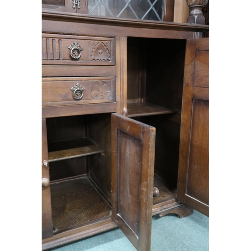 87 - A 20th century beech court style sideboard with inset cabinet door flanked by leaded glass panels ov... 