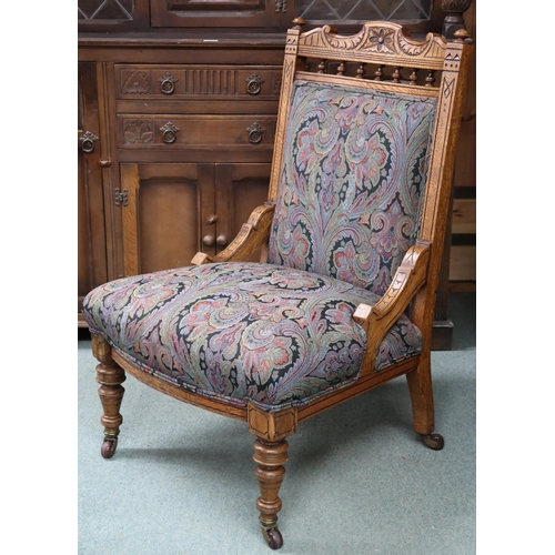 91 - A Victorian oak framed nursing chair with damask upholstery on turned supports terminating in cerami... 