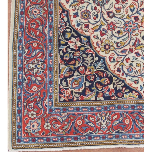 2132 - A CREAM FLORAL PATTERNED GROUND SAROUGH RUG with mustard central medallion, dark blue spandrels and ... 