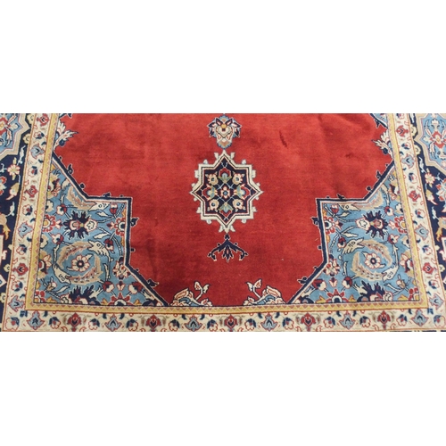 2134 - A RED GROUND TABRIZ RUG with dark blue central medallion, light blue spandrels and dark blue borders... 