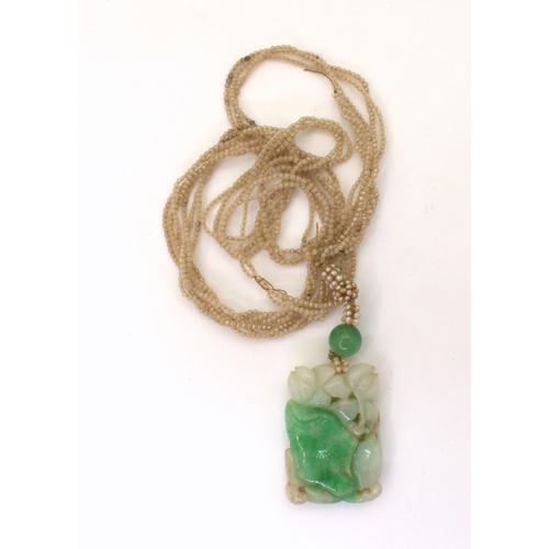 2729 - A CHINESE GREEN HARDSTONE PENDANTcarved with foliage, with further hardstone bead (7.5mm) and glass ... 