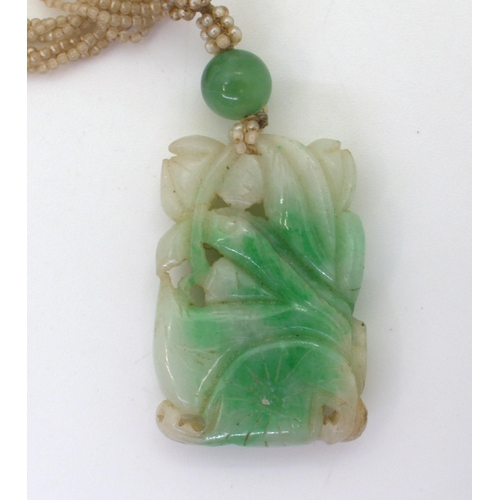 2729 - A CHINESE GREEN HARDSTONE PENDANTcarved with foliage, with further hardstone bead (7.5mm) and glass ... 