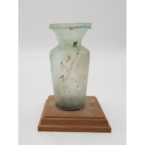 2365A - A ROMAN GLASS CONTAINER in green with funnel shaped neck and ridged lip,13cm high,an early Chri... 