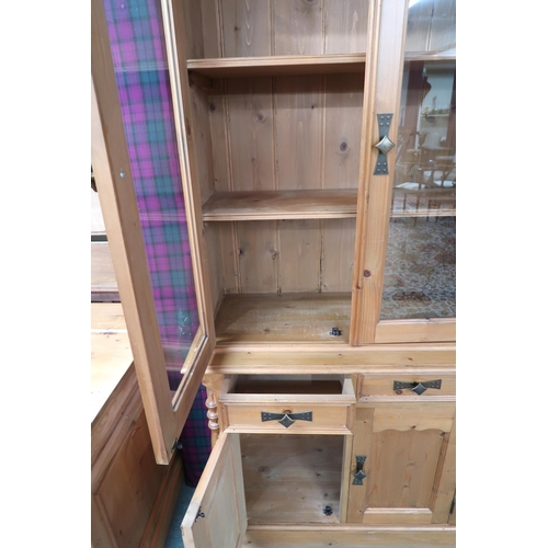 33 - A contemporary pine bookcase with moulded cornice over pair of glazed doors on base with two short d... 