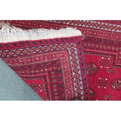 66 - A red ground Bokhara style prayer mat/rug with multiple borders, 122cm long x 79cm wide 