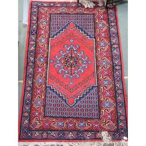 69 - A red ground Hamadan rug with blue central medallion, dark blue spandrels and multicoloured borders,... 