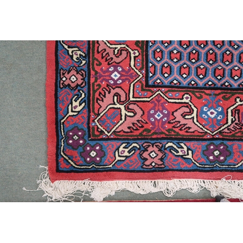 69 - A red ground Hamadan rug with blue central medallion, dark blue spandrels and multicoloured borders,... 