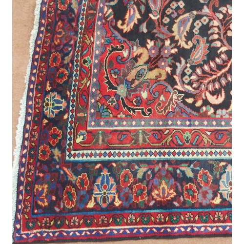 37 - A BLACK FLORAL FOLIATE PATTERNED GROUND LILIHAN RUG with red central medallion, matching spandrels a... 