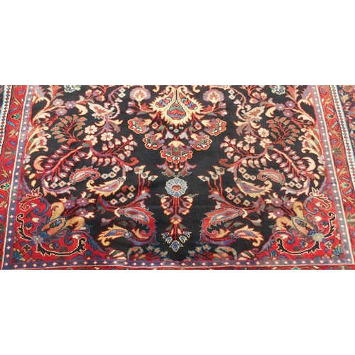 37 - A BLACK FLORAL FOLIATE PATTERNED GROUND LILIHAN RUG with red central medallion, matching spandrels a... 