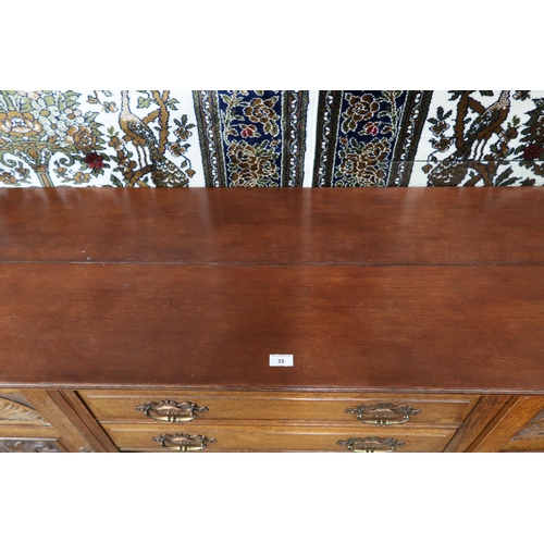 35 - A late Victorian oak sideboard with two central drawers over pair of carved cabinet doors flanked by... 