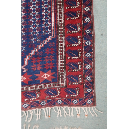 64 - A blue ground Balouch rug with geometric patterned central ground and red and blue geometric border,... 