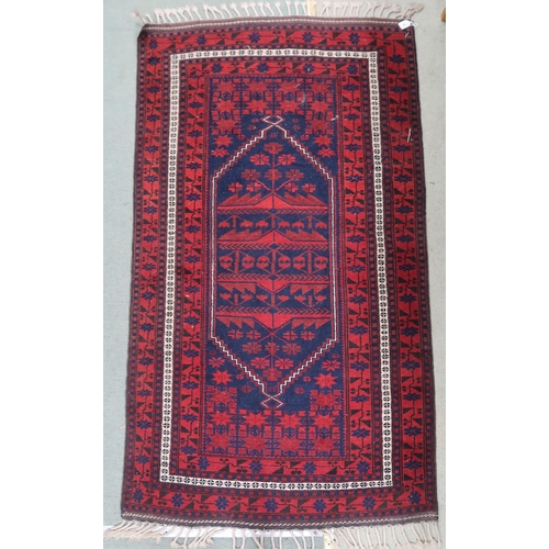 65 - A dark blue ground Balouch rug with red geometric central pattern and red geometric border, 198cm lo... 