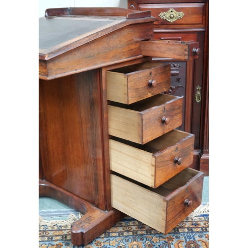 16 - A Victorian rosewood Davenport writing desk with hinged writing slope top over four drawers to right... 