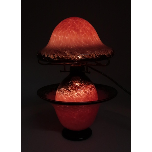 200 - A Monart style glass table lamp, the bulbous base with mushroom shaped shade, in mottled pink with b... 