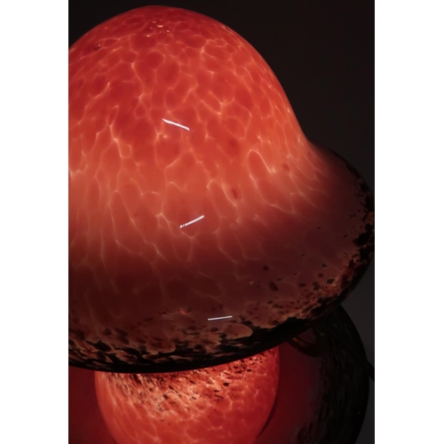 200 - A Monart style glass table lamp, the bulbous base with mushroom shaped shade, in mottled pink with b... 