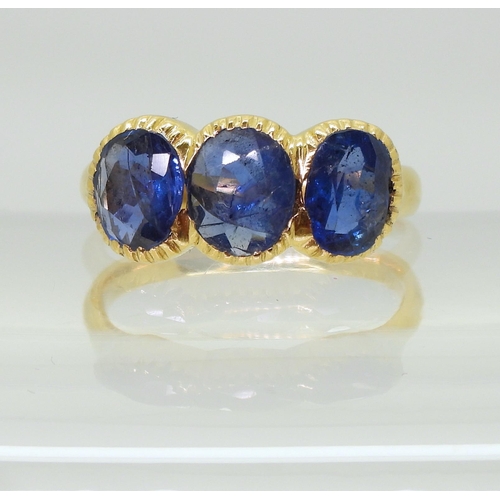 712 - A three stone sapphire ring, mounted in bright yellow metal, in pretty cut back bezel settings, fing... 