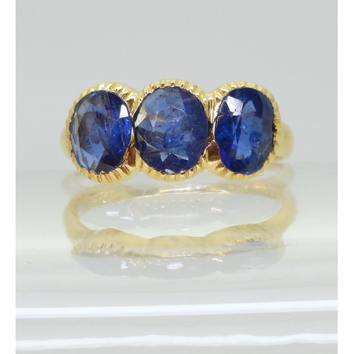 712 - A three stone sapphire ring, mounted in bright yellow metal, in pretty cut back bezel settings, fing... 