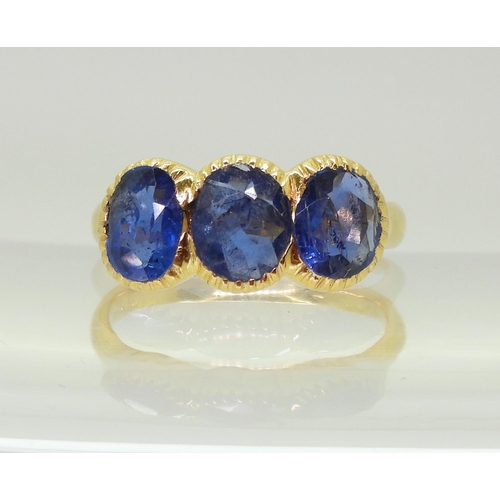 712 - A three stone sapphire ring, mounted in bright yellow metal, in pretty cut back bezel settings, fing... 