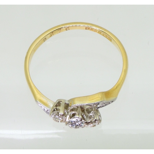 713 - An 18ct and platinum vintage three stone diamond ring, with pretty on a twist design, set with estim... 