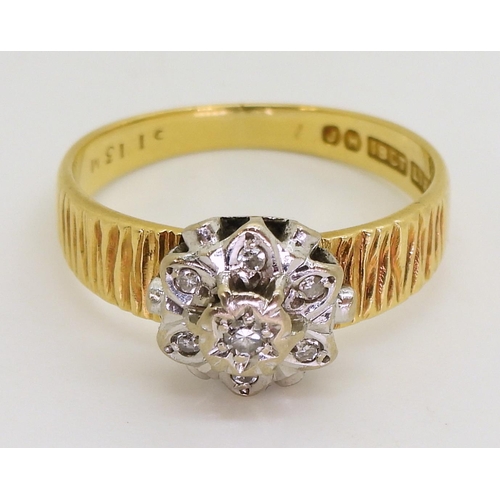 750 - An 18ct gold diamond retro flower ring set with diamond accents, and bark textured shoulders, finger... 