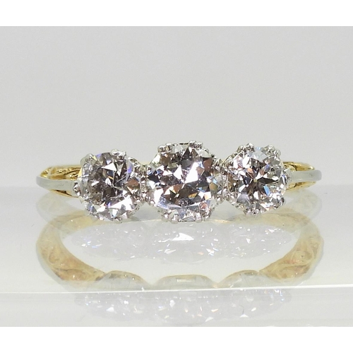 753 - A 1930s vintage three stone diamond ring, with a pretty platinum and 18ct yellow gold scroll mount, ... 