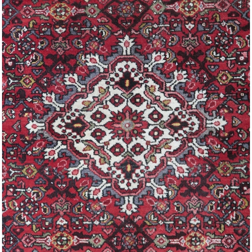 18 - A red ground hamadan rug with cream central medallion, matching spandrels and multiple borders, 162c... 