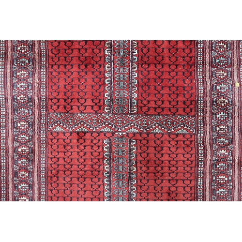 28 - A red ground Turkaman rug with four panelled ground with multicoloured geometric border, 190cm long ... 